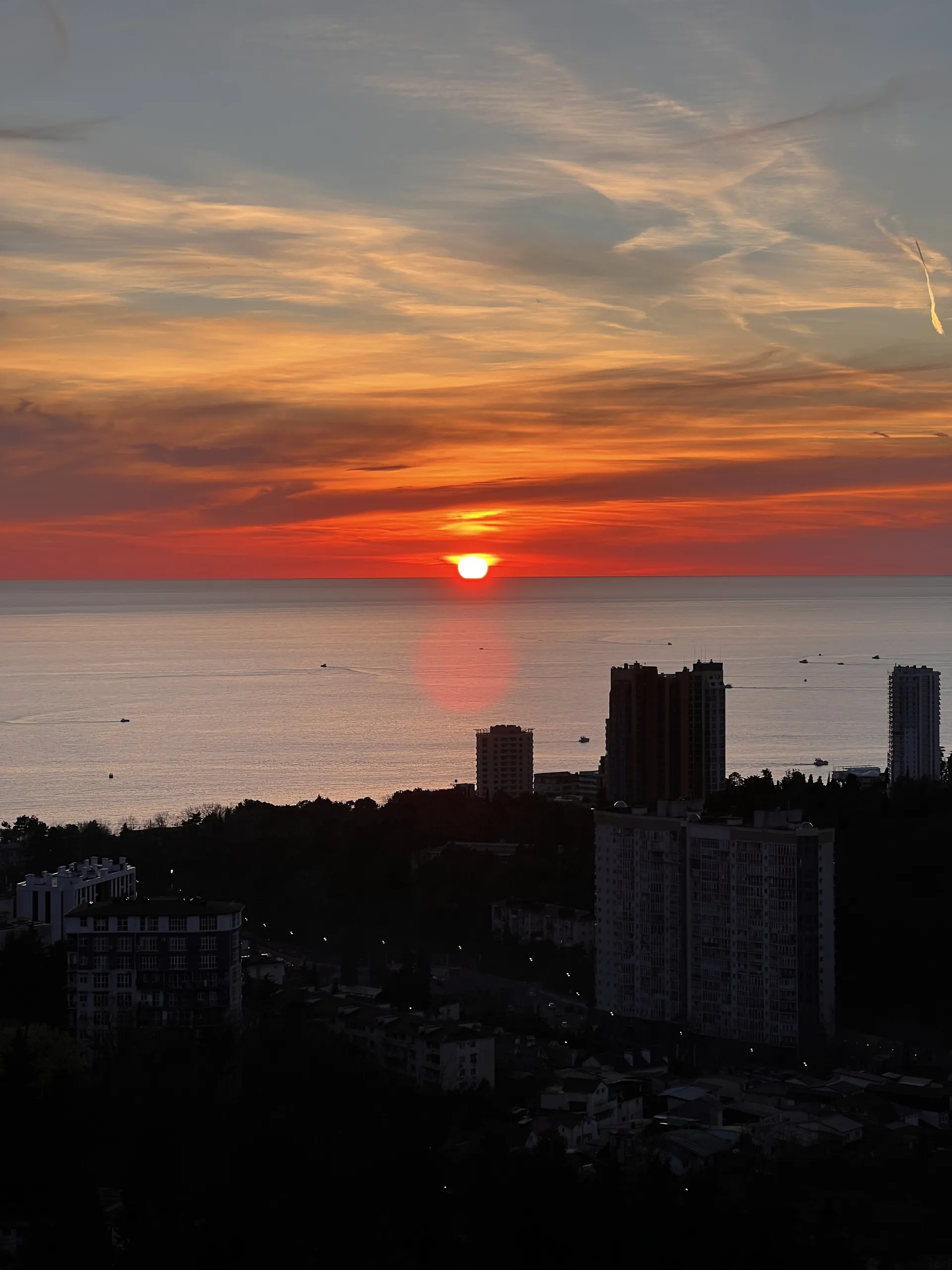 Солнце садится в море, панорама города с террасы